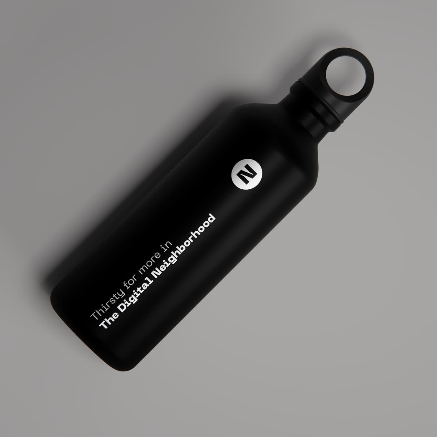 A black reusable water bottle with a looped cap lies on a grey surface. The bottle features white text reading, Thirst for more in The Digital Neighbourhood, and a circular N logo.