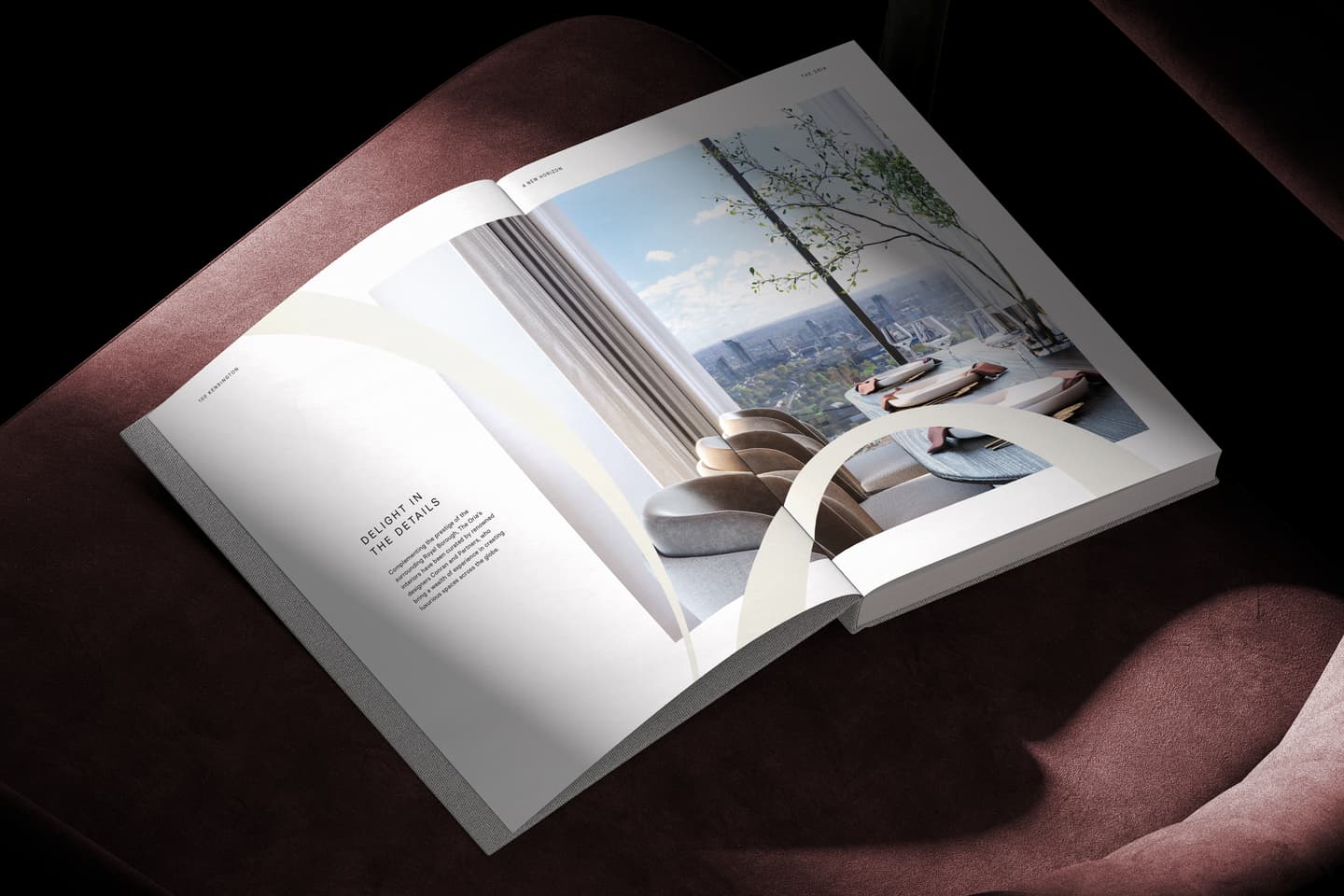 An open magazine rests on a maroon chair, displaying a page with text on the left and a modern dining room with a city view on the right.