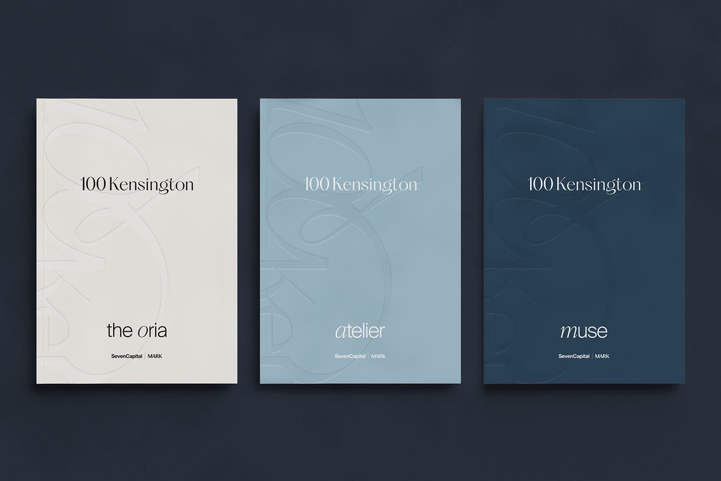 Three minimalist brochures for 100 Kensington are displayed side by side in white, light blue, and dark blue, labelled the oria, atelier, and muse.