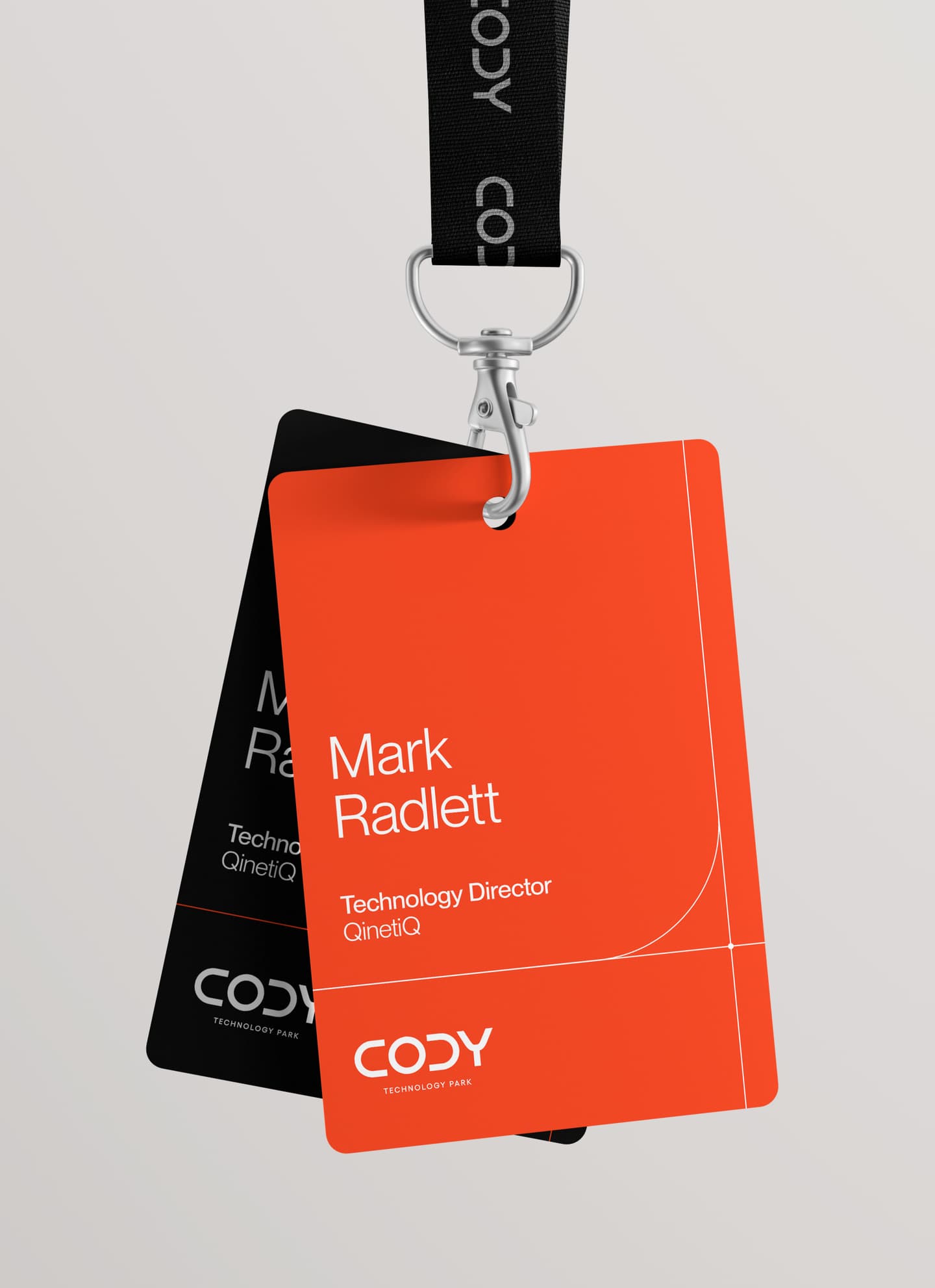 A lanyard holds two ID badges, with the front badge showing the name Mark Radlett, Technology Director at QinetiQ, and the CODY logo on an orange background.