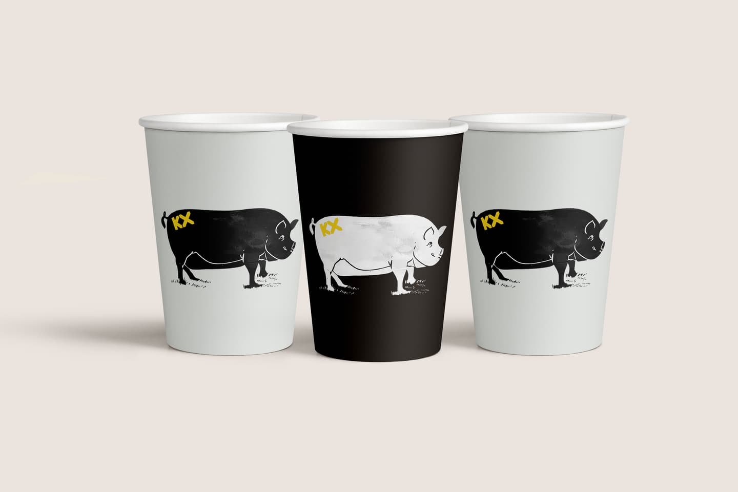 Three paper cups featuring a black and white ox illustration with yellow KKX text, one cup is black and the other two are white.