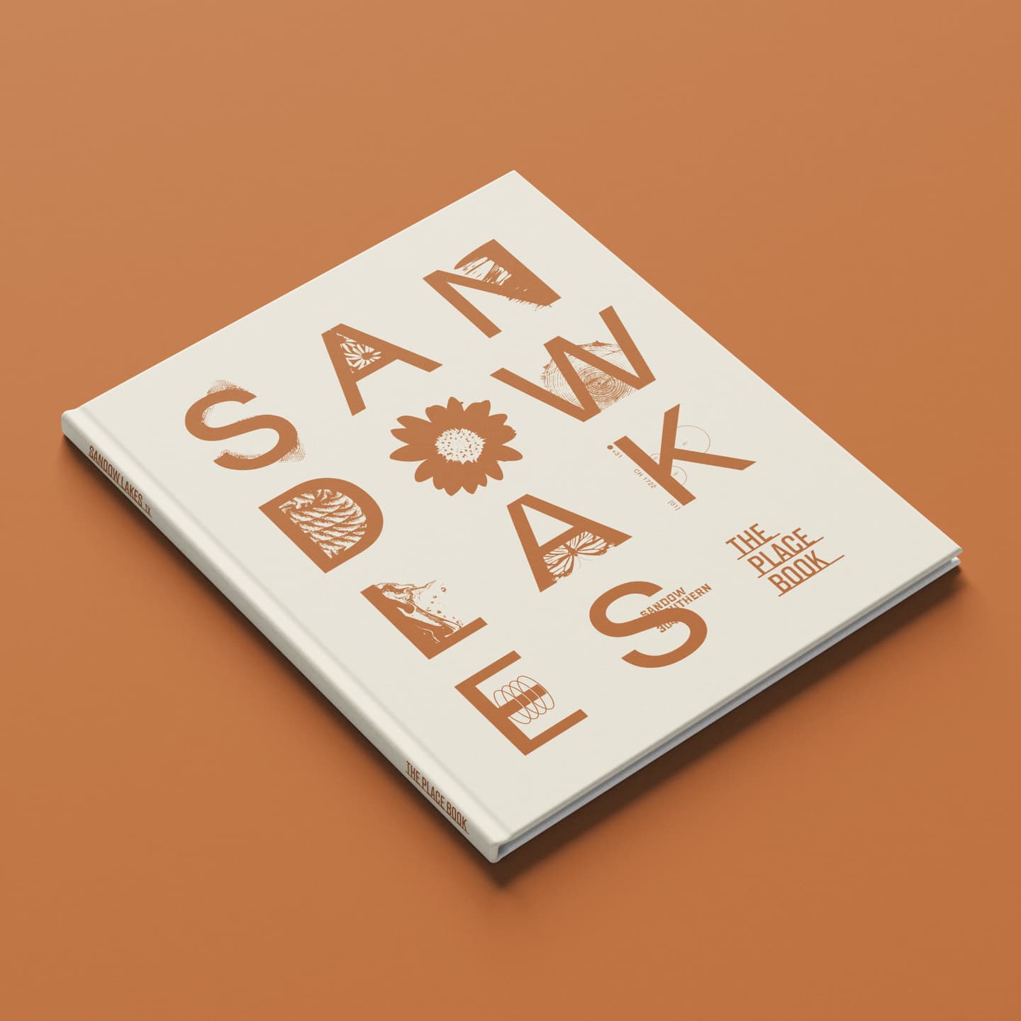 A hardback book titled SAND OAKS with large tan letters and plant illustrations on a white cover, lying on a brown surface.