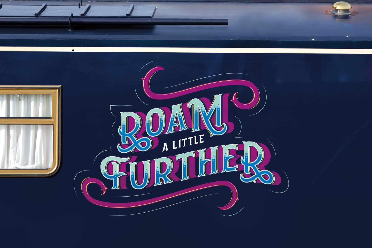The side of a dark blue vehicle displays colourful lettering that reads Roam a Little Further next to a window with white curtains.