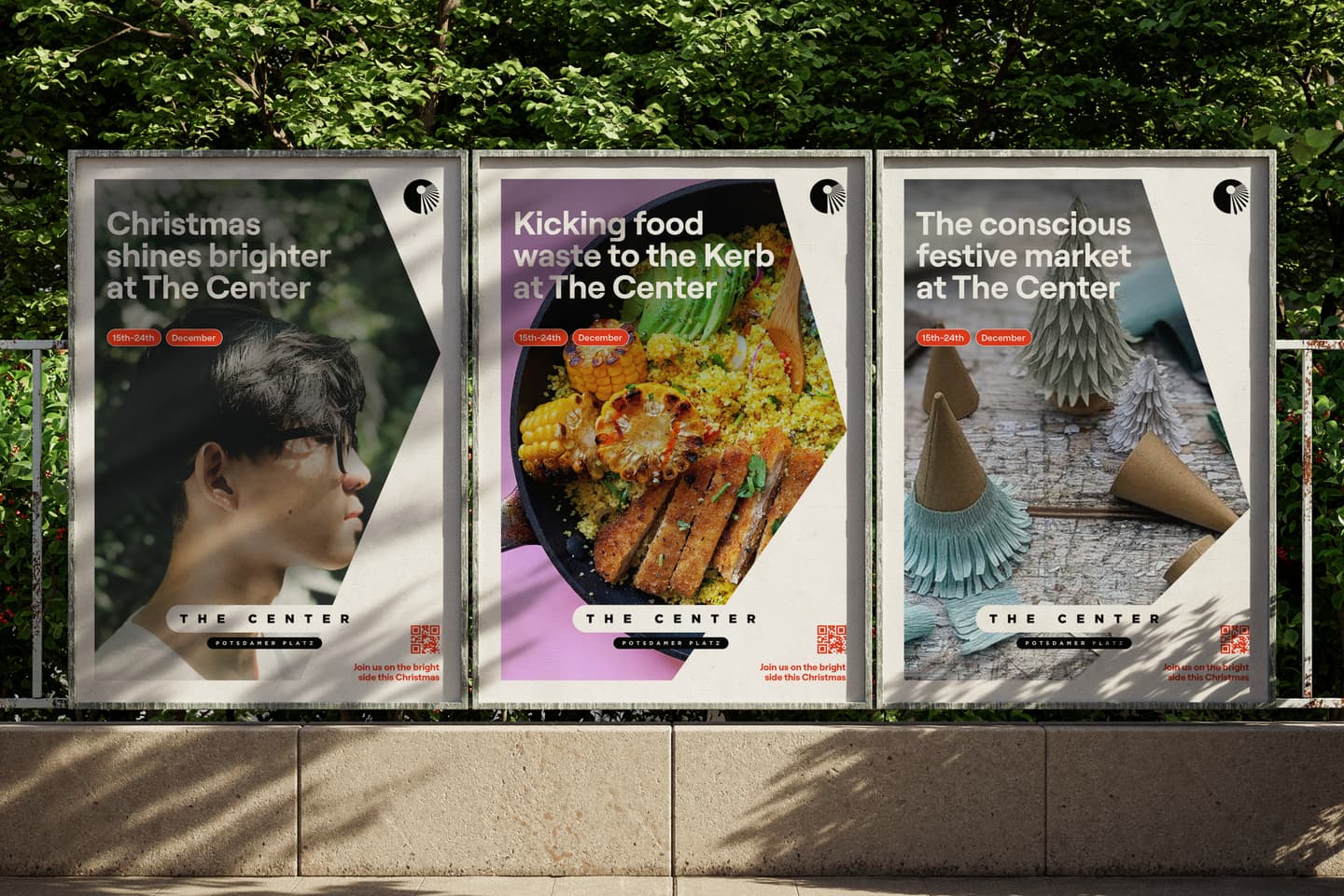 Three posters on a pavement promote Christmas events, food waste initiatives, and a festive market at The Centre, with trees and sunlight in the background.